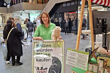 Eine Frau mit einem Aufsteller an einem Infostand
